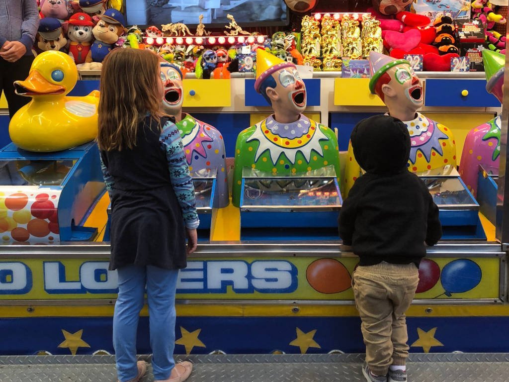 Children in front of laughing clowns fairground game